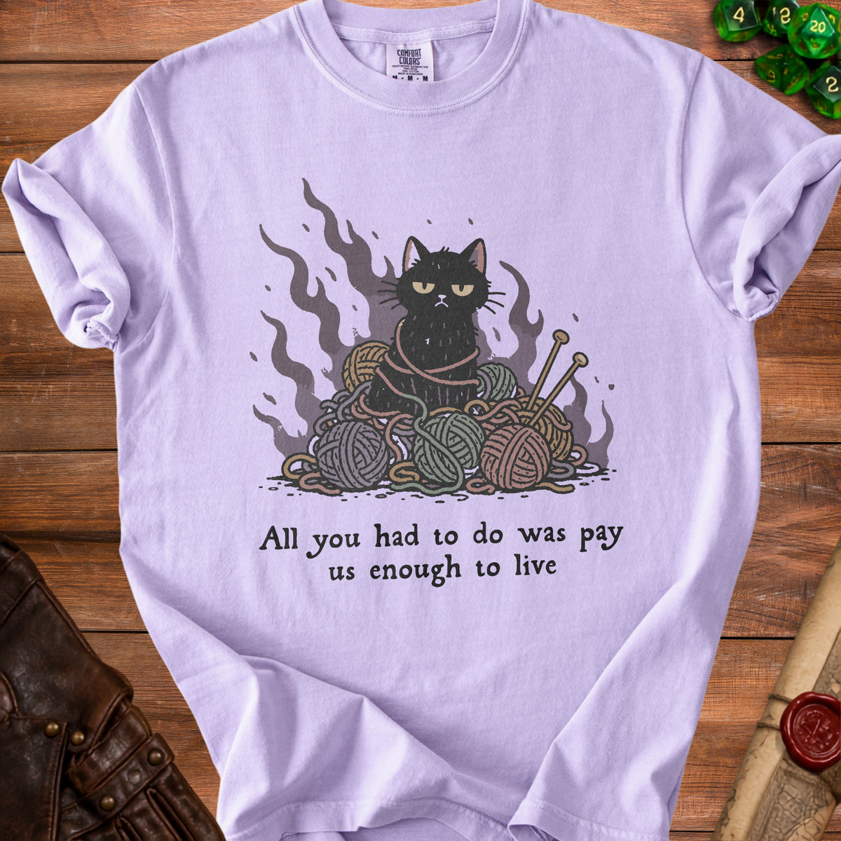 Lilac t-shirt with black cat tangled in yarn and quote: "All you had to do was pay us enough to live."