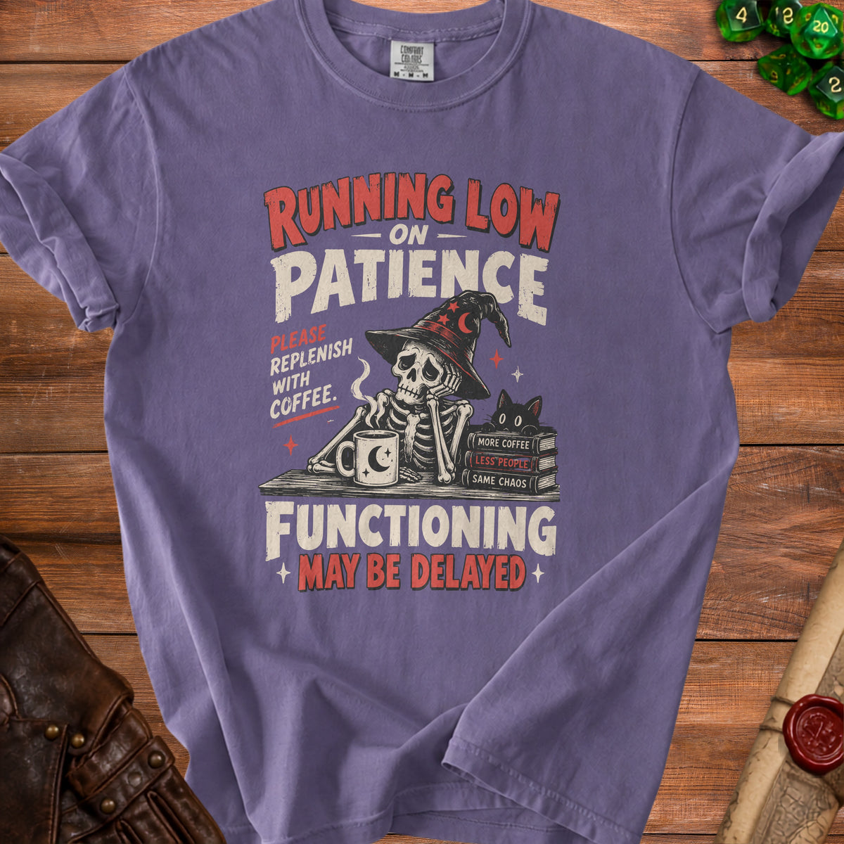 Purple t-shirt graphic: Skeleton with witch hat, coffee, black cat, books, and text.