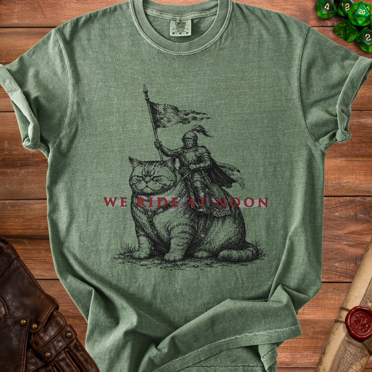 Green t-shirt with knight riding a cat graphic and text "We Ride at Noon".
