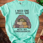 Mint green t-shirt with illustration of a character under a blanket, with text.