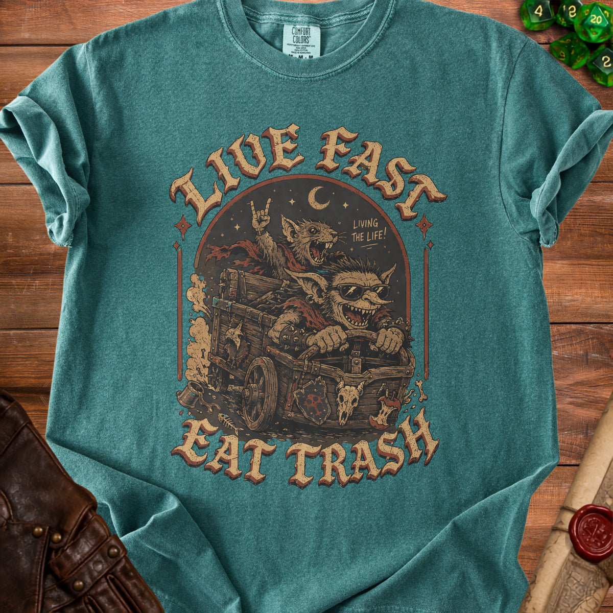 Green t-shirt with "Live Fast Eat Trash" text and cartoon creatures in a cart.