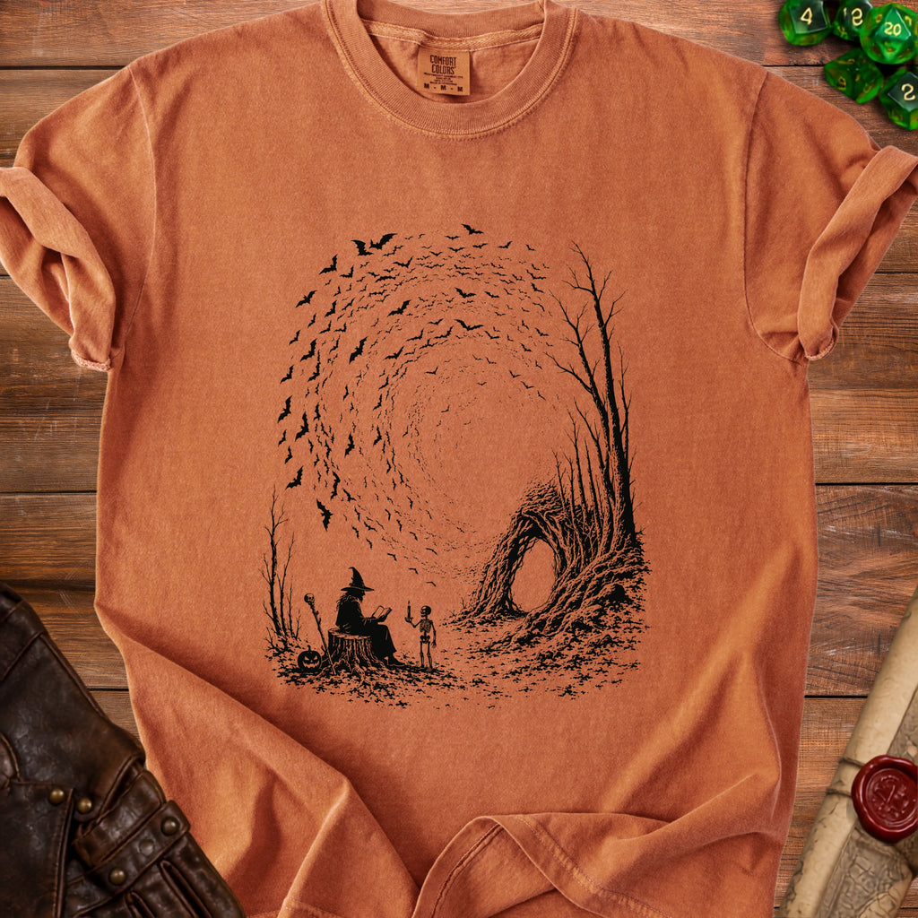 Orange t-shirt with Halloween graphic of a witch, skeleton, and swirling bats.