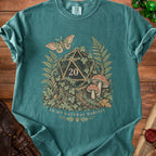Teal t-shirt with a D20 die, moth, mushrooms, ferns, and "In My Natural Habitat" text.