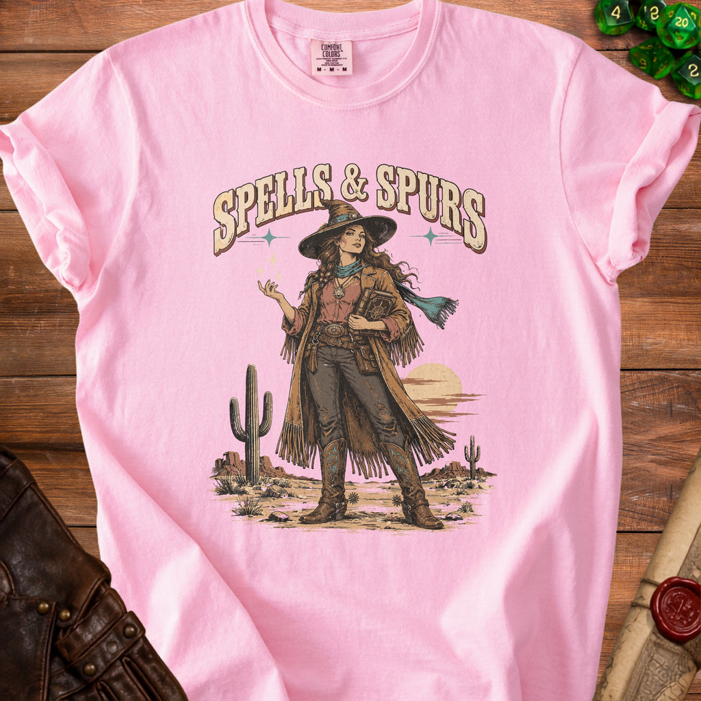 Pink t-shirt with "Spells & Spurs" text and desert witch illustration.