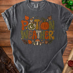 Dark gray t-shirt with "Potion Weather" text, potion bottle, pumpkin, and mushrooms.