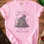 Pink t-shirt with a knight illustration and the text "Under this hard exterior lies a Silly lil guy".