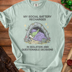 Light blue t-shirt with goblin sleeping in cave text "MY SOCIAL BATTERY RECHARGES IN ISOLATION AND QUESTIONABLE DECISIONS".