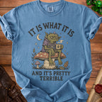 Blue t-shirt with artwork of a grumpy goblin on a mushroom holding a skull mug.