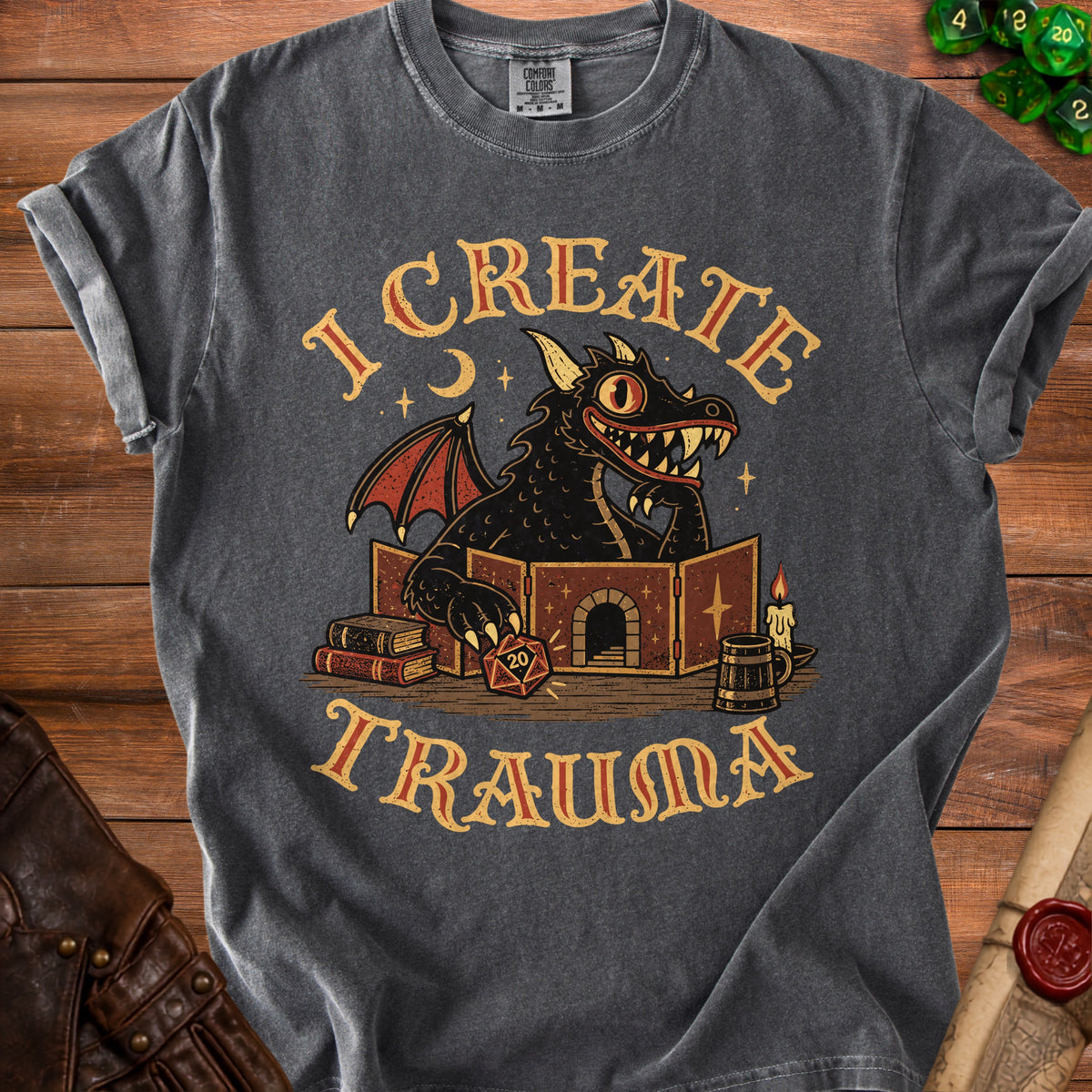 A dark gray t-shirt featuring a cartoon dragon behind a dungeon master screen with text reading I CREATE TRAUMA.
