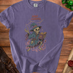 Purple t-shirt featuring skeleton wizard with book and text "Abra Cadaver."