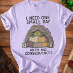 Lilac t-shirt with cartoon creature and text: "I NEED ONE SMALL DAY WITH NO CONSEQUENCES."