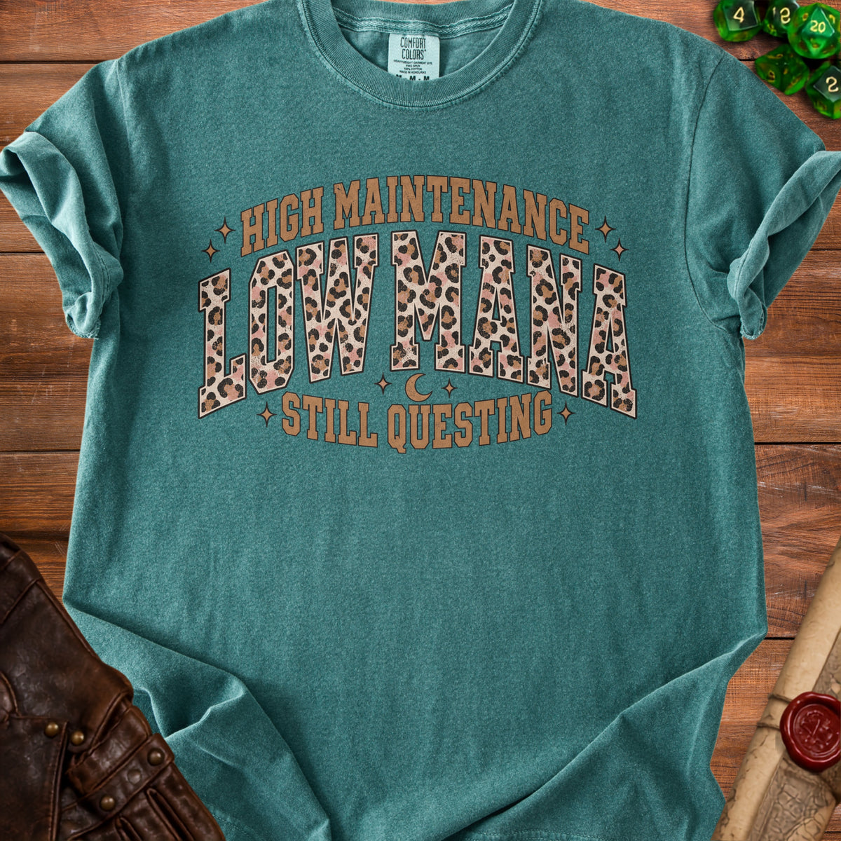 Teal t-shirt with "HIGH MAINTENANCE LOW MANA STILL QUESTING" text in leopard print.