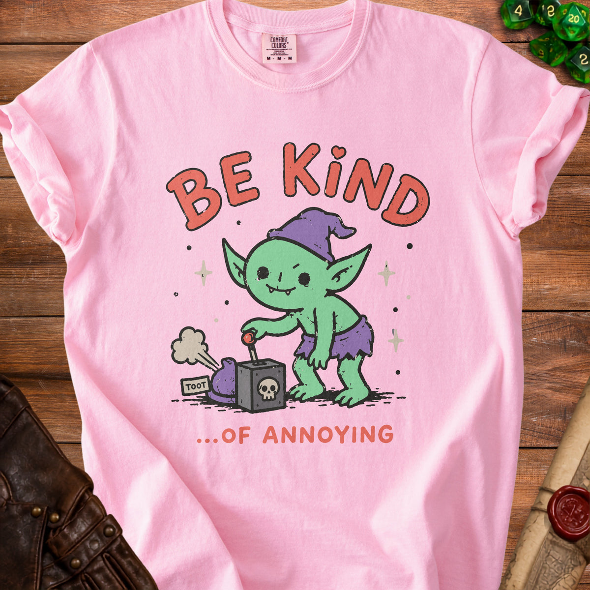 Pink t-shirt with a cartoon goblin activating a device that says "TOOT" and text "BE KIND ...OF ANNOYING".