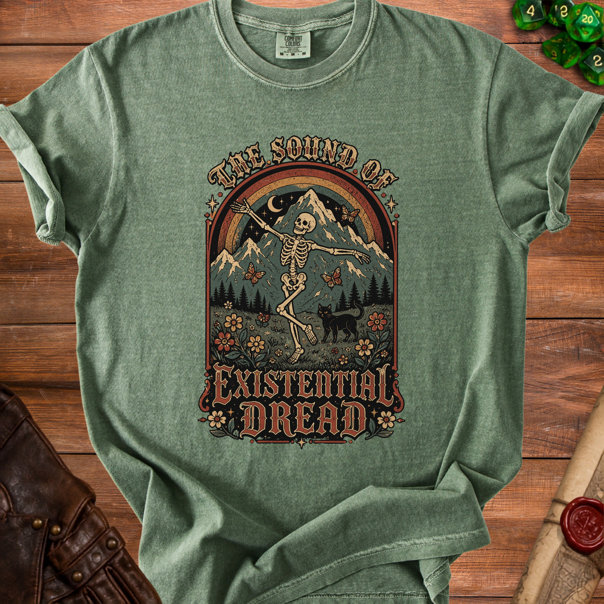 Green t-shirt with graphic of dancing skeleton, mountains, and text "The Sound of Existential Dread."