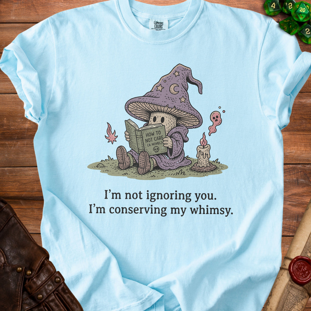 Light blue t-shirt with a mushroom wizard reading "How to Not Care" and text "I'm not ignoring you. I'm conserving my whimsy."