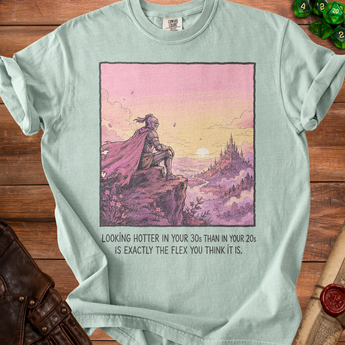 Light blue t-shirt with knight overlooking castle and text: "Looking hotter in your 30s than in your 20s is exactly the flex you think it is."