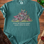 Teal t-shirt graphic of a knight in armor drinking tea with text "Even the bravest knight needs a little lie down."