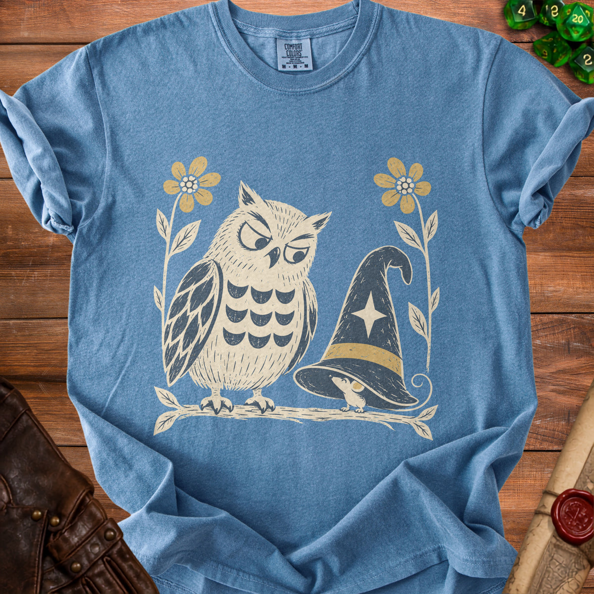 Blue t-shirt with an owl, witch hat, mouse, and flowers graphic.