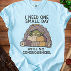 Light blue t-shirt with a goblin under a star-patterned blanket, text says "I NEED ONE SMALL DAY WITH NO CONSEQUENCES."