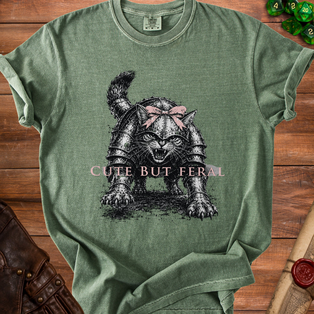 Green t-shirt with armor-clad cat graphic and pink text "CUTE BUT FERAL".