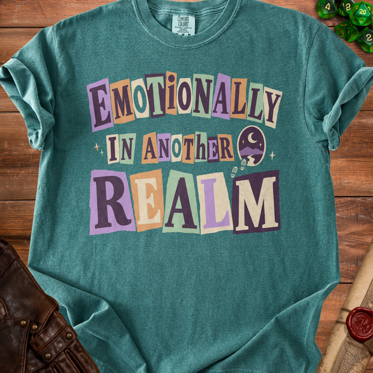 Teal t-shirt with "Emotionally In Another Realm" text and moon graphic.