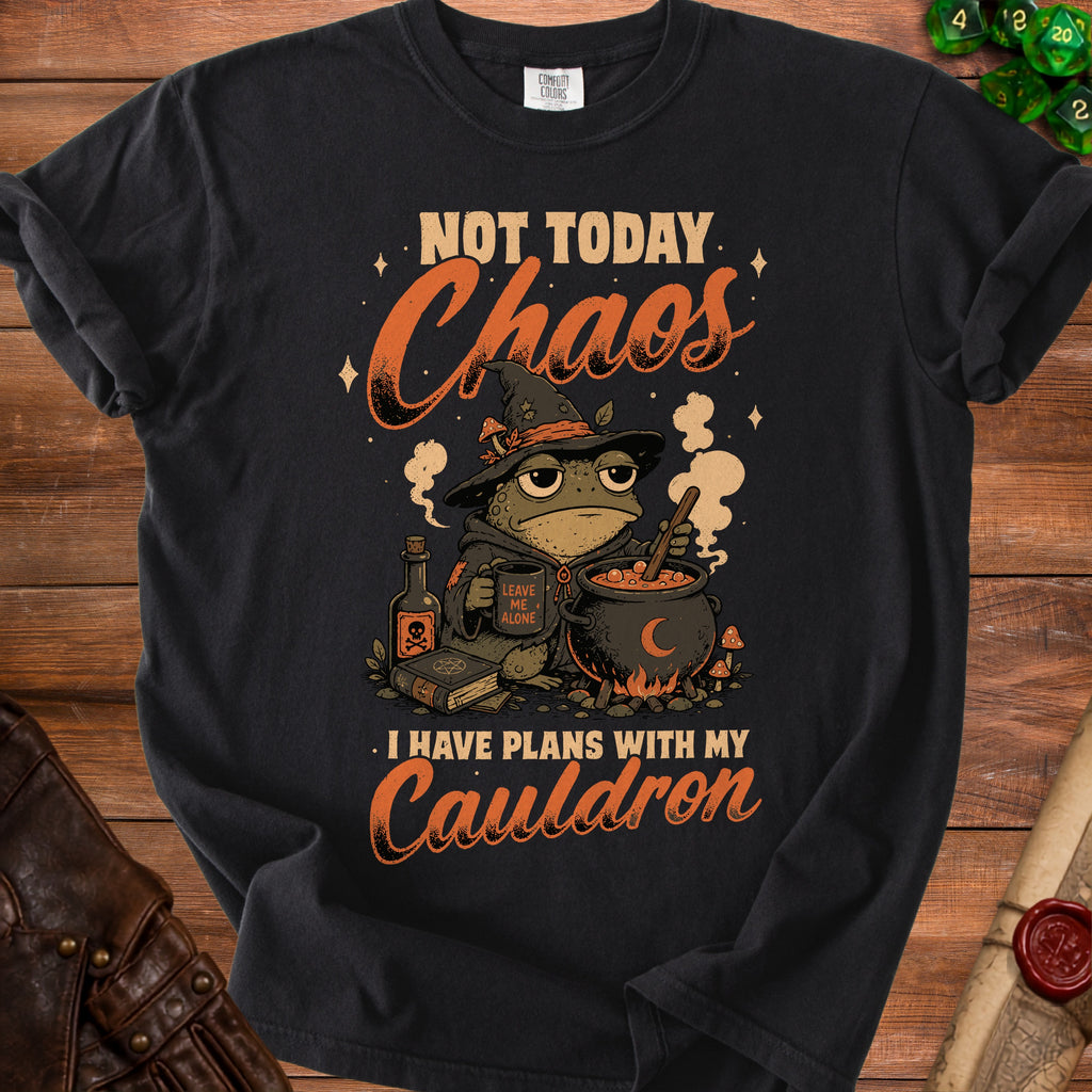 Black t-shirt with a cartoon frog wizard holding a mug and cauldron. Text says "Not Today Chaos. I Have Plans With My Cauldron."