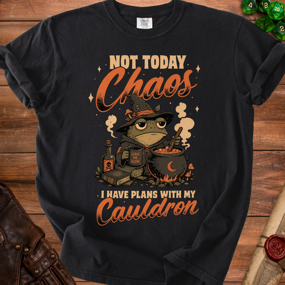 Black t-shirt with a cartoon frog wizard holding a mug and cauldron. Text says "Not Today Chaos. I Have Plans With My Cauldron."
