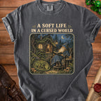 Dark t-shirt with "A Soft Life In A Cursed World" text above wizard and dragon illustration.
