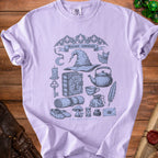 Lilac t-shirt with "Hermit essentials" graphic featuring wizard hat and various magical items.