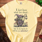 Yellow t-shirt with illustration of a goblin, lantern, and text "I don't know what lies ahead... but I do know it will be an adventure".