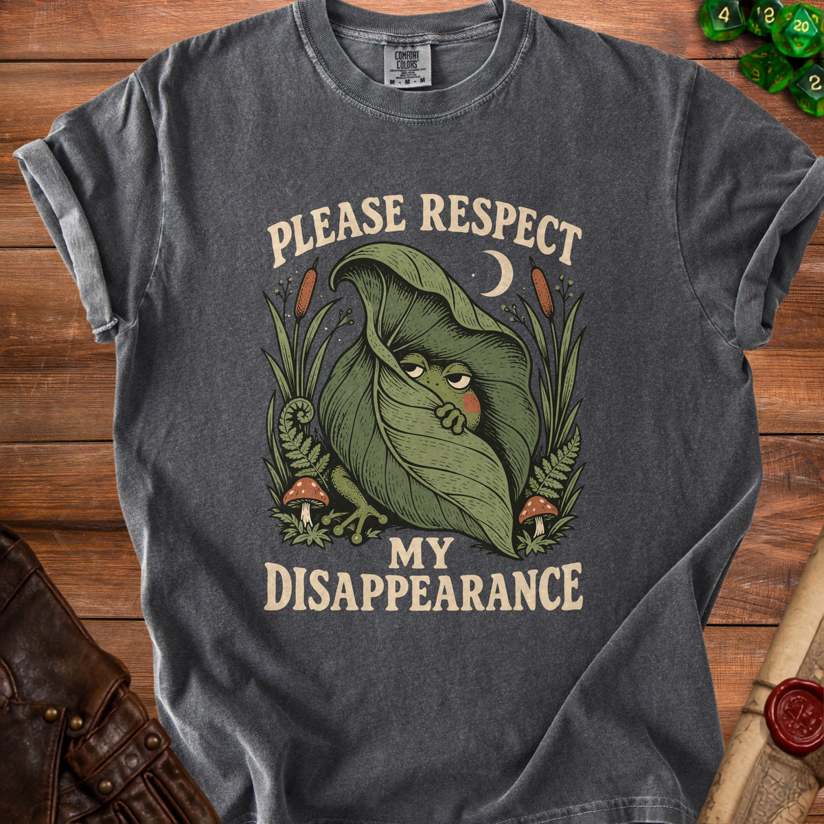 Dark grey t-shirt with a graphic of a frog peeking from a leaf and text "PLEASE RESPECT MY DISAPPEARANCE".
