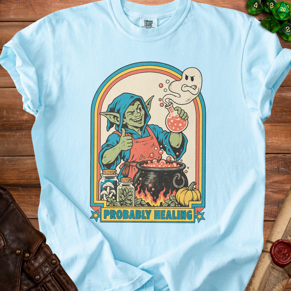 Light blue t-shirt with a goblin brewing potion under a rainbow arch.