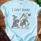 Light blue t-shirt with "I CAST BONK!" and a wizard hitting a skeleton with a club.