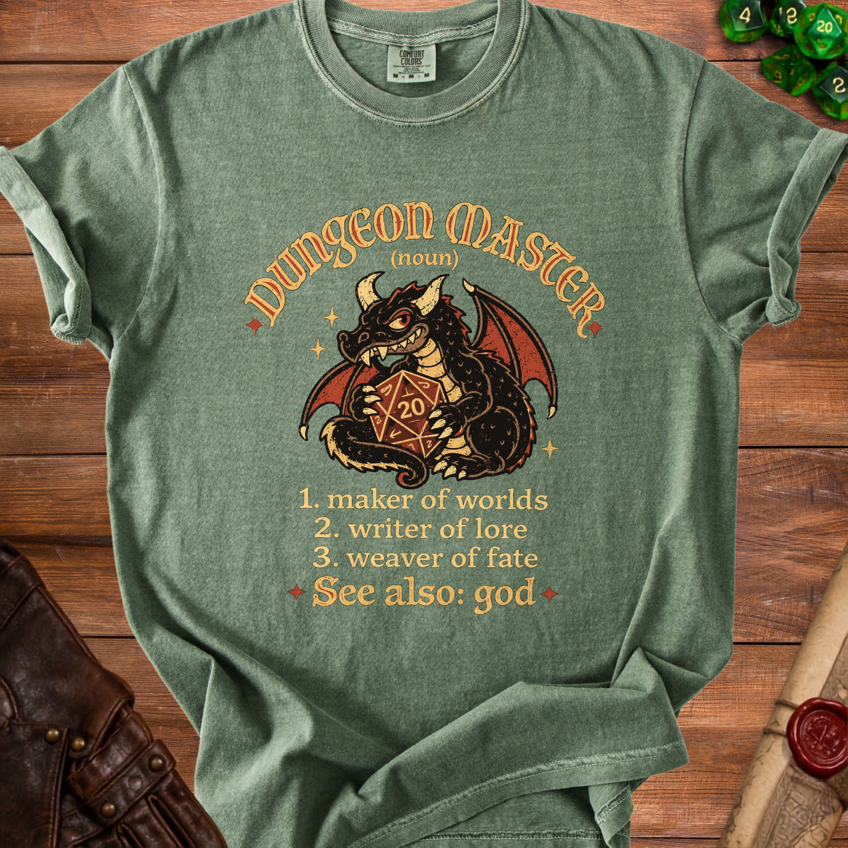 Olive green t-shirt with graphic of a dragon holding a twenty-sided die and text defining Dungeon Master.