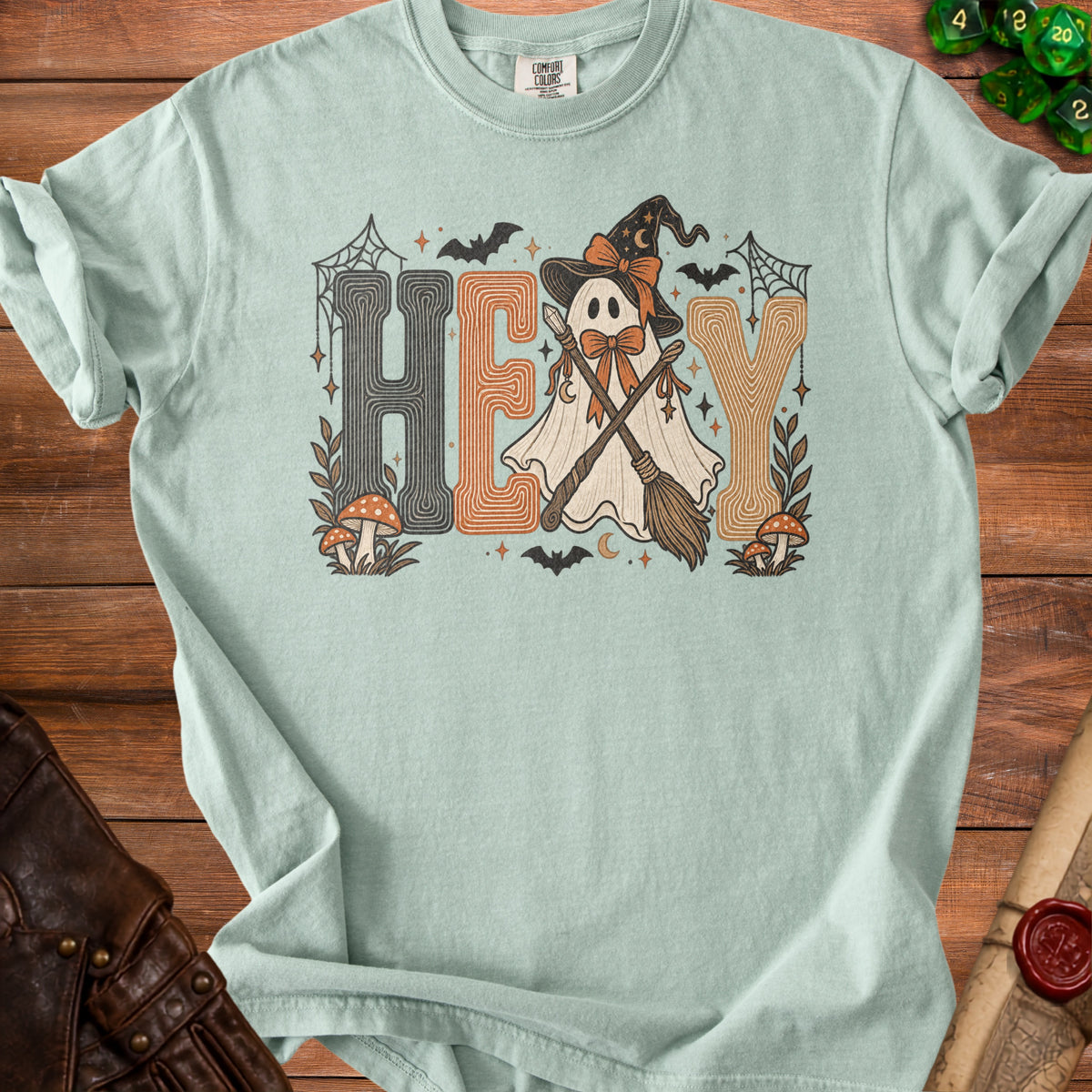 Light blue t-shirt with "HEY" and a ghost wearing a witch hat and holding brooms.