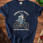 T-shirt with wizard on bicycle graphic and text "Powered by Pedals and Questionable Magic".