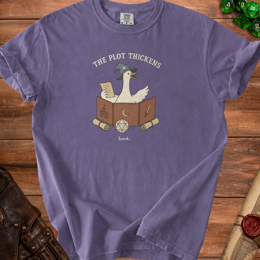 T-shirt with goose in wizard hat, game master screen, dice, and text "The plot thickens."