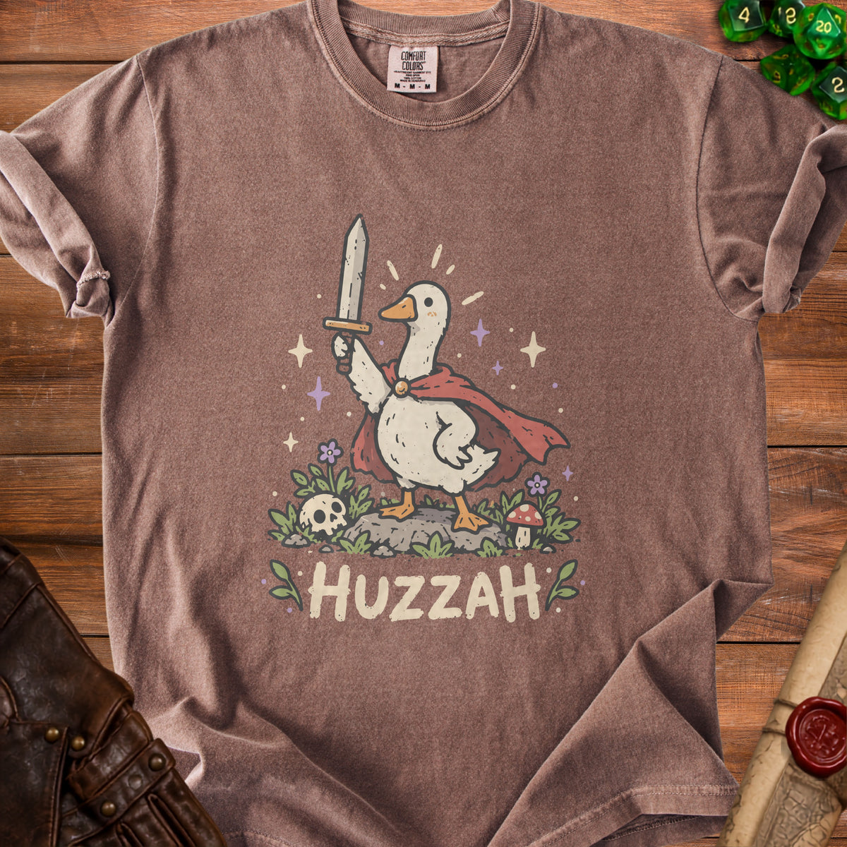 Brown t-shirt with a cartoon goose wearing a cape, holding a sword, and the word "HUZZAH".