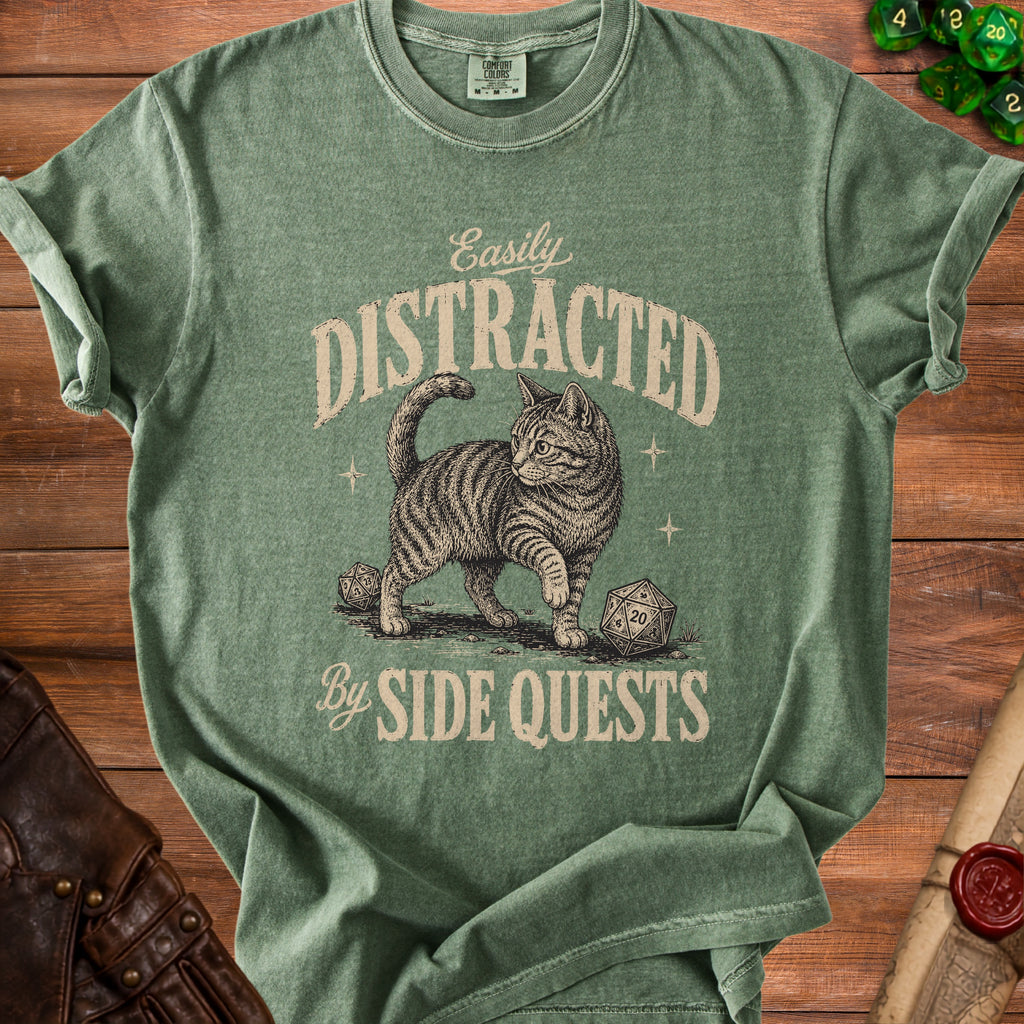 Green t-shirt with a drawing of a cat and dice, reading "Easily Distracted By Side Quests".