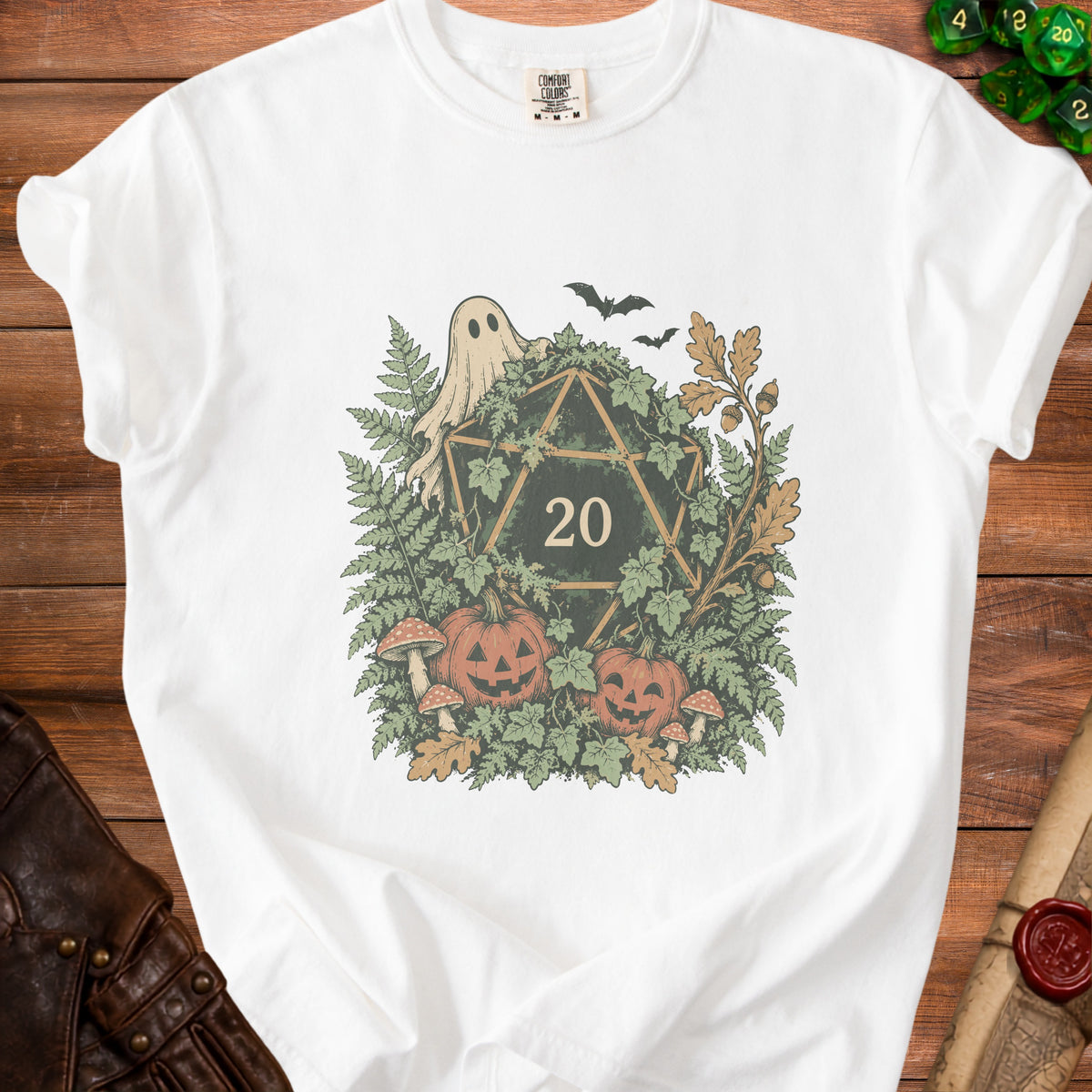 White t-shirt with a Halloween-themed graphic featuring a d20 die, ghost, bats, pumpkins, and foliage.
