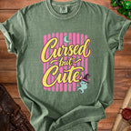 Green t-shirt with "Cursed but Cute" text and a ghost wearing a witch hat.