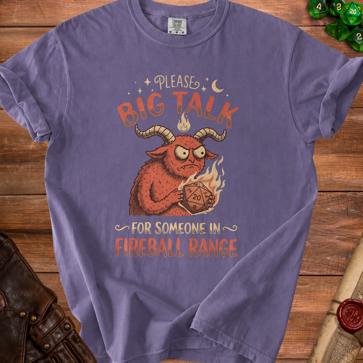 Purple t-shirt with a horned monster holding a twenty-sided die and the text "BIG TALK FOR SOMEONE IN FIREBALL RANGE".