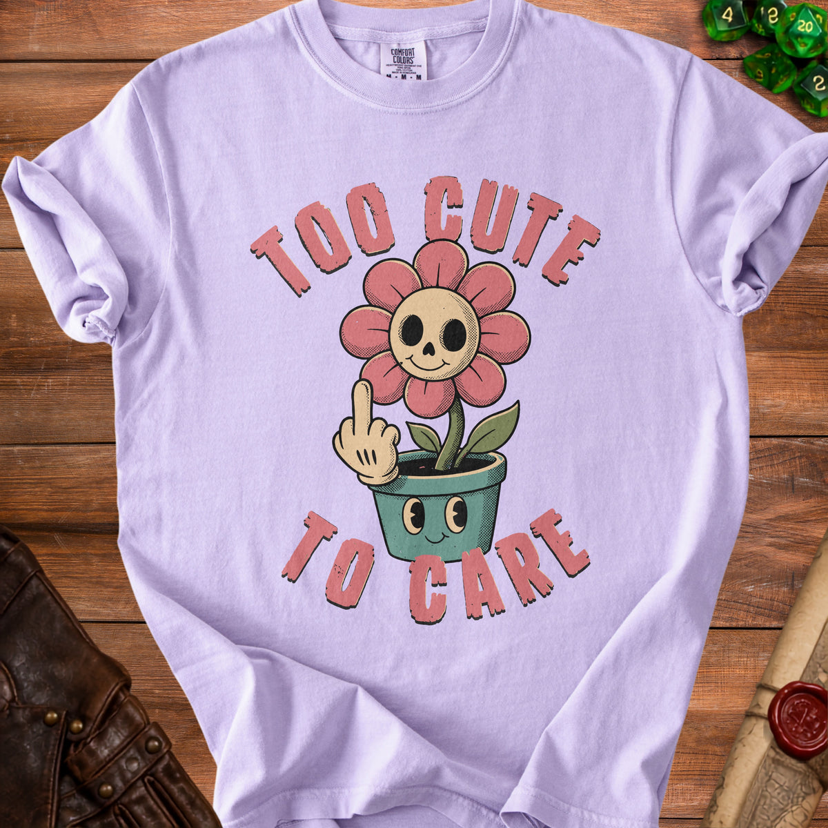 Purple t-shirt with "Too Cute To Care" text and a skull flower giving the middle finger.