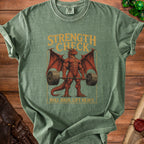 Green t-shirt with a red muscular dragon lifting weights, text reads "STRENGTH CHECK" and "ROLL HIGH. LIFT HEAVY.".