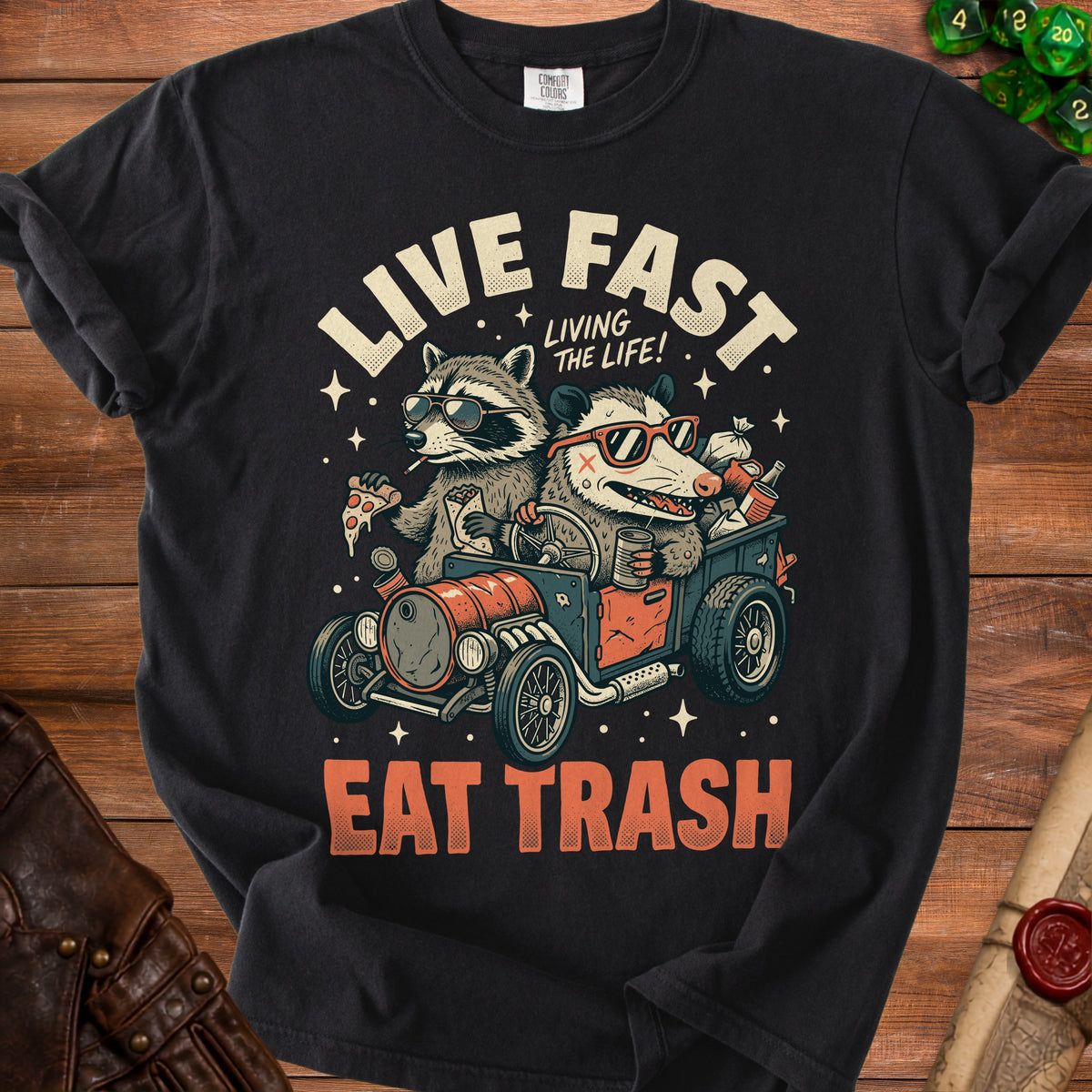 Black t-shirt with raccoons driving a car and text "Live Fast Eat Trash".