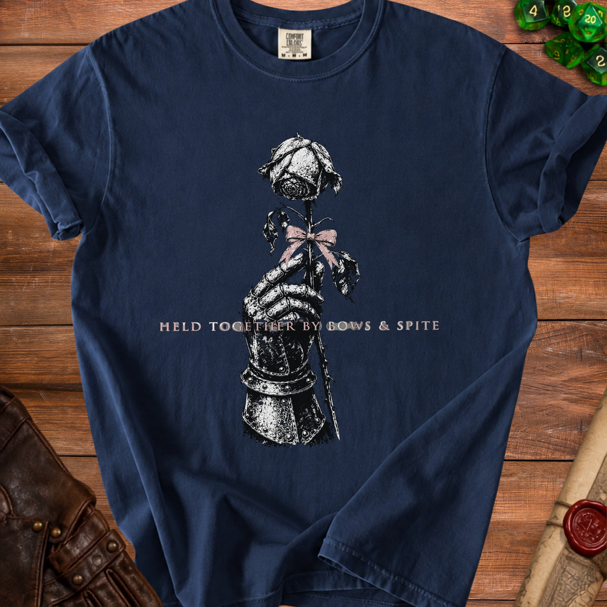 Dark blue t-shirt with a knight's gauntlet holding a rose, with text "HELD TOGETHER BY BOWS & SPITE".