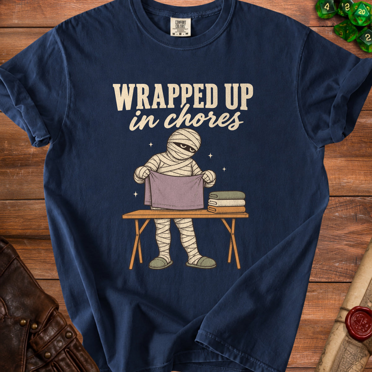 Navy t-shirt with text "WRAPPED UP in chores" and a mummy character folding laundry.