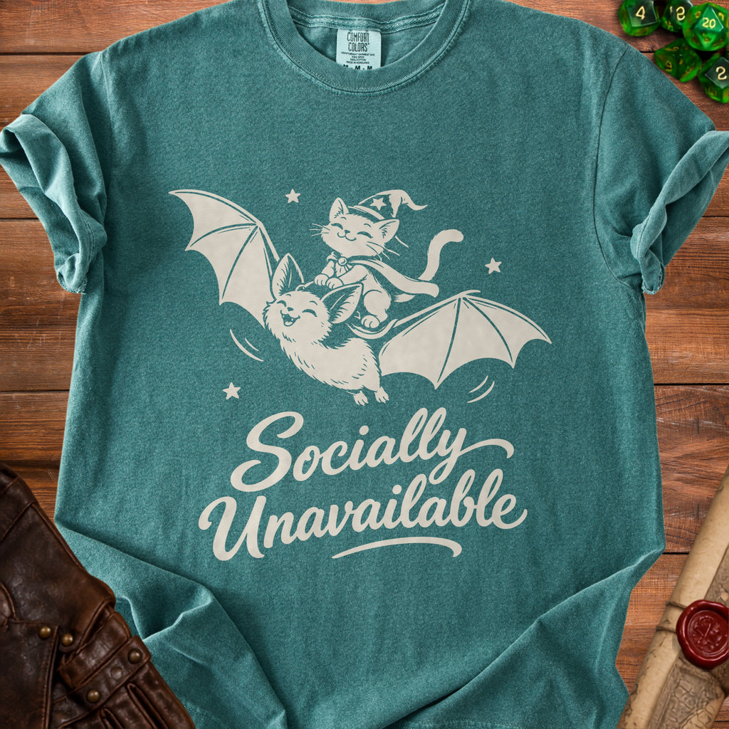 Green t-shirt with white graphic of cat on bat and text "Socially Unavailable".