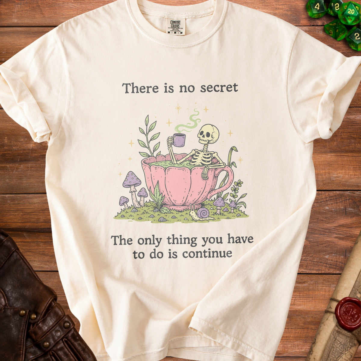 Cream t-shirt with skeleton in teacup graphic and text "There is no secret. The only thing you have to do is continue."