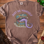 T-shirt graphic with a monster treasure chest and the text "JUST BE YOURSELF".